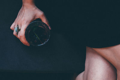 Midsection of woman holding glass while sitting on sofa