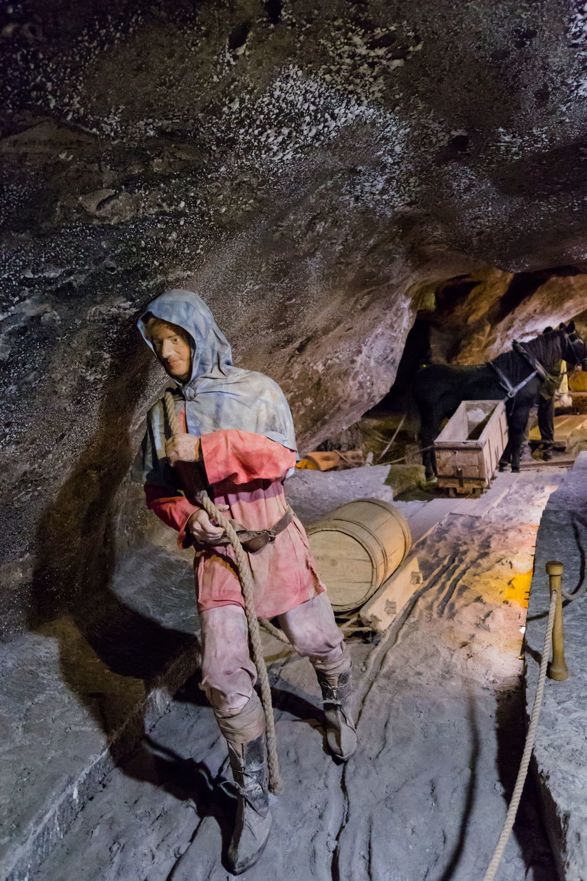 REAR VIEW OF MAN WORKING ON ROCKS