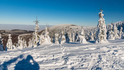 Panoramic view of snow covered land against blue sky