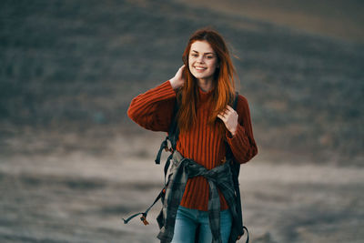 Portrait of smiling young woman standing against sea