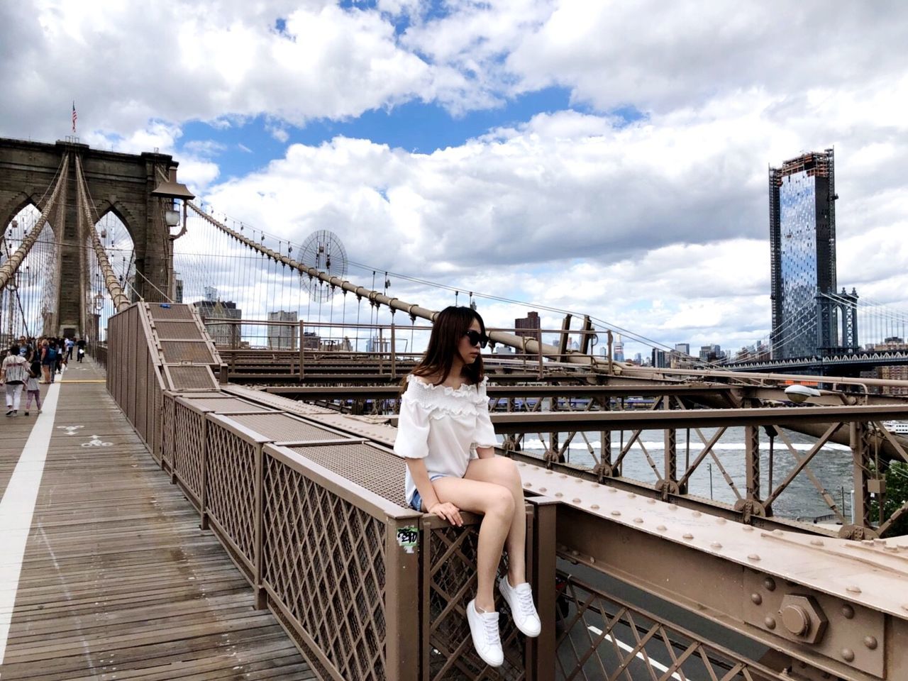 built structure, architecture, bridge, bridge - man made structure, cloud - sky, sky, connection, real people, one person, railing, lifestyles, transportation, sitting, women, full length, young women, young adult, adult, nature, day, hairstyle, footbridge, outdoors