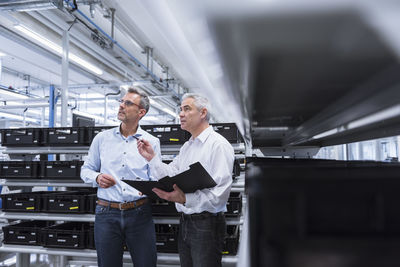 Two managers with files standing in comany, discussing