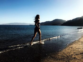 Woman running at beach against sky