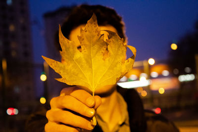 Close-up portrait of person holding illuminated lighting equipment at night