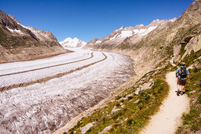 Rear view of backpacker walking on mountain road