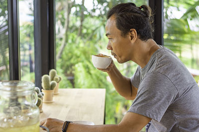 Side view of man drinking coffee cup on table