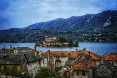 Buildings by lake against sky