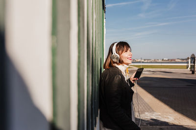 Happy woman listening to music on headse houses.promenade costa nova, aveiro, portugal