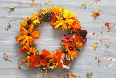 High angle view of orange flowers wreath on table for decoration