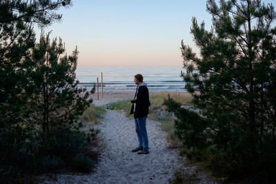 Rear view of man standing by sea against sky