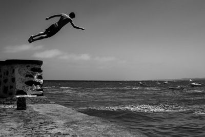 Man jumping over sea against sky