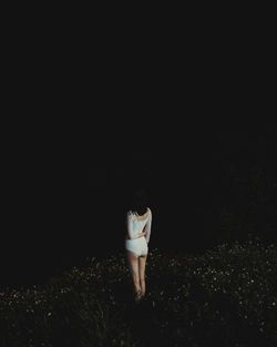 Rear view of woman standing on field at night