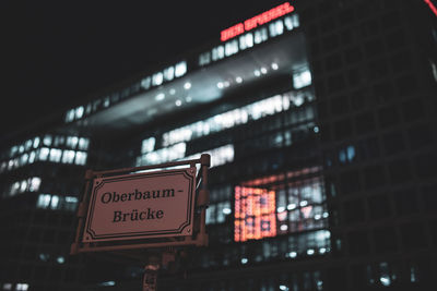 Low angle view of illuminated sign on building at night