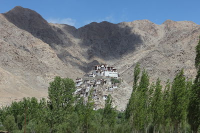 Low angle view of houses on hill against rocky mountains