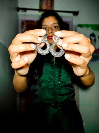 Portrait of young woman holding camera while standing at home