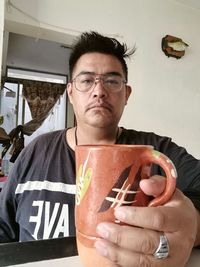 Portrait of young man holding eyeglasses