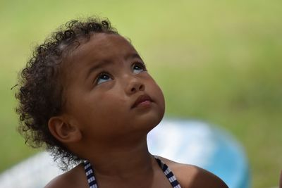 Close-up of cute baby girl looking up while standing outdoors