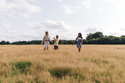 Friends enjoying while walking on meadow at park