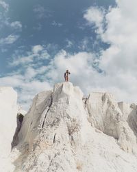 Low angle view of woman on white rock formation against sky