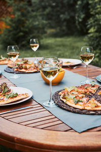 Dinner in a home garden. pizza, salads, fruits and white wine on table in a orchard in a backyard