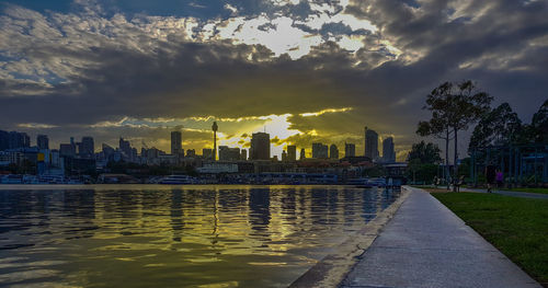 River and buildings against sky during sunset