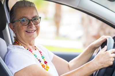 Portrait of smiling senior woman sitting in car