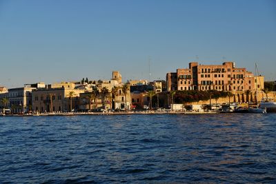 Sea by buildings against clear blue sky