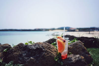 Close-up of mocktail on the rocks by sea against clear sky