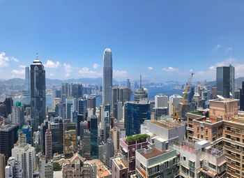 Aerial view of buildings in city against blue sky