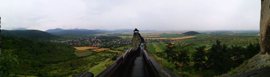 Panoramic view of walkway leading towards observation point by farms against clear sky