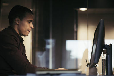 Side view of businessman using computer at desk in dark office