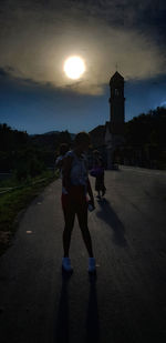 Rear view of people on road against sky during sunset