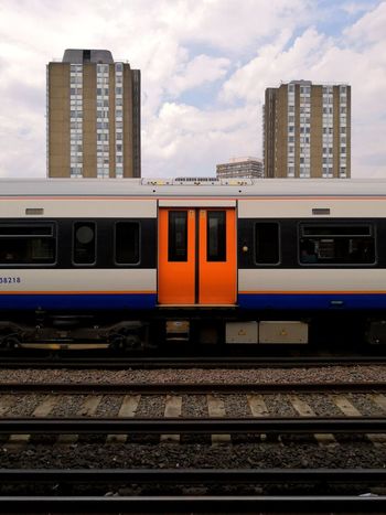 Train on railroad track in city against cloudy sky