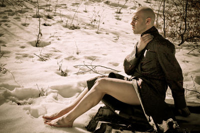 Side view of boy sitting in snow