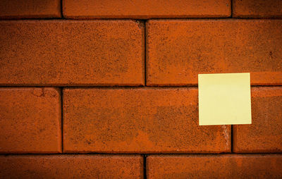 Blank yellow note on brick wall