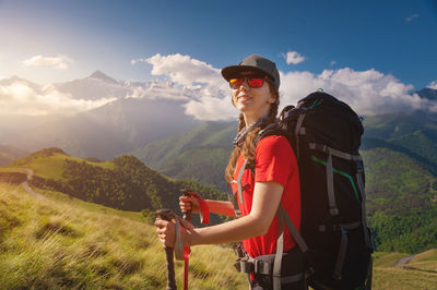 Portrait of young smiling woman trekking against mountains and sky