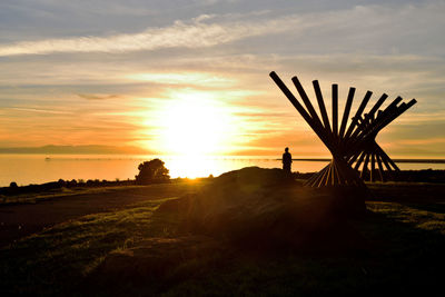 Silhouette person on field against sky during sunset