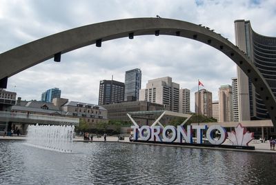 Bridge over river in city against sky