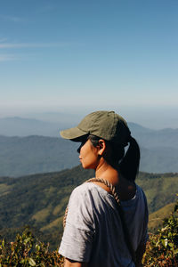 Side view of man looking at mountains against sky