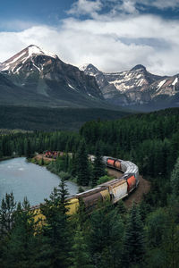 Scenic view of train towards snowcapped mountains against sky