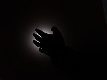 Close-up of silhouette hand against black background