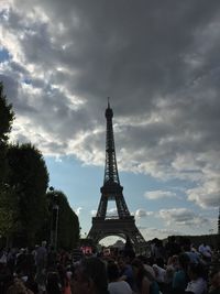 Tourists in front of historic building against cloudy sky