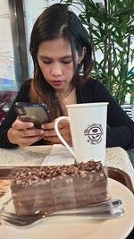 Young woman using phone while sitting on table