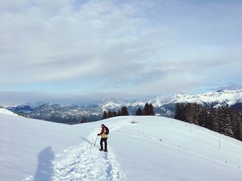 Man skiing on snowcapped mountain against sky