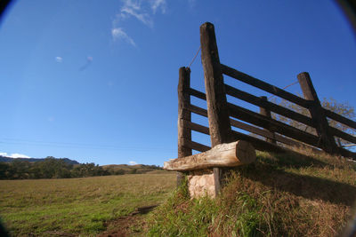 Wooden structure on field against blue sky