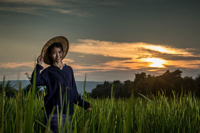 Portrait of woman standing on field against sky during sunset