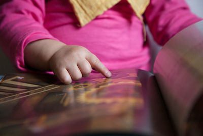 Midsection of baby girl pointing finger on book