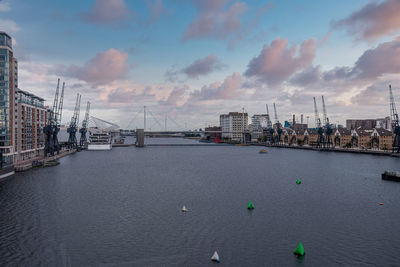 Port cranes with cityscape alongside river thames at royal victoria dock