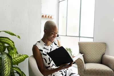 Casual businesswoman sitting in armchair writing in her journal