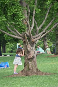 Side view full length of girl standing by tree at park